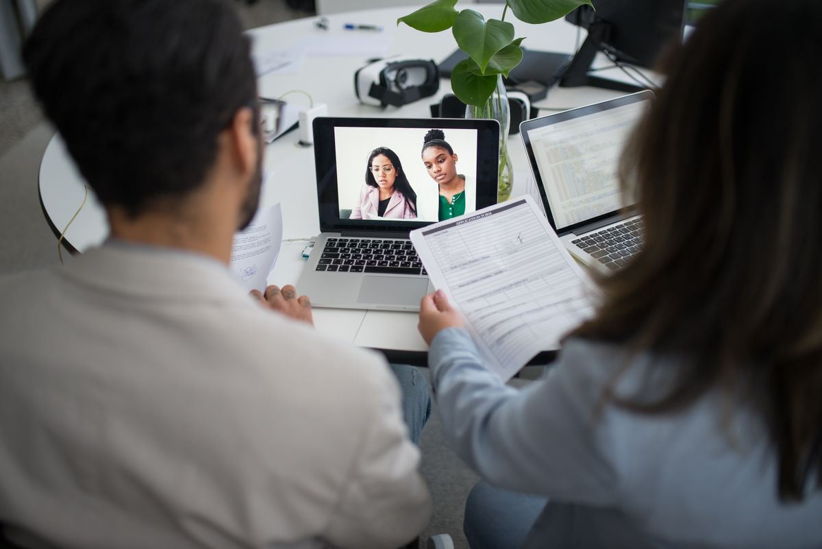 Two professionals on a video call interview using laptops