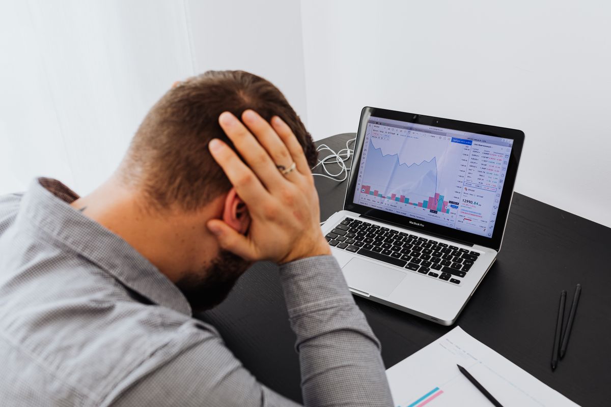 Stressed person looking at declining charts on a laptop